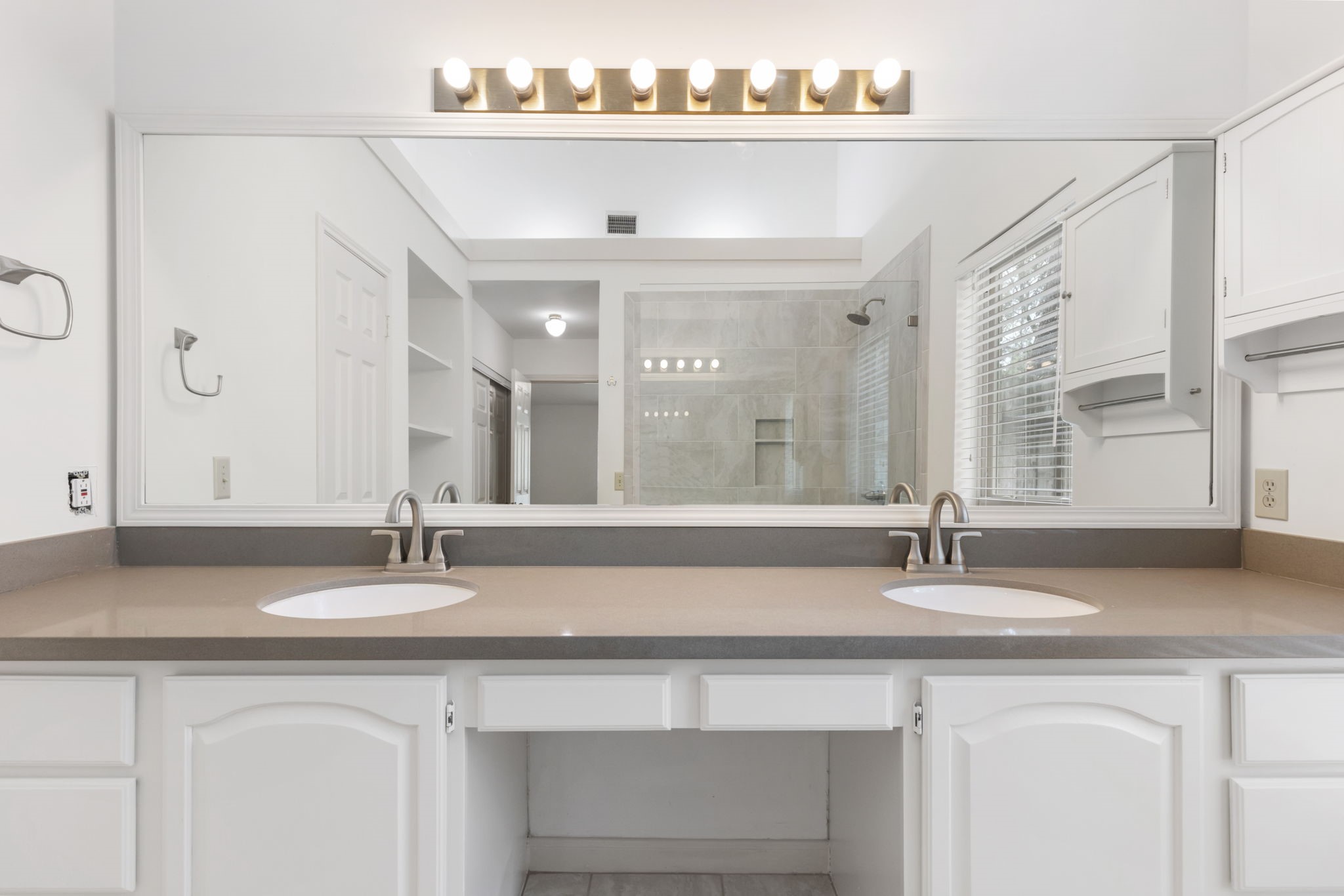 59 Fire Flicker Place Spring, TX 77381 - Photo 19 of 37 This bathroom features a spacious dual vanity with sleek countertops and modern faucets, enhanced by a large mirror and overhead lighting, while the glass-enclosed shower adds a contemporary touch.