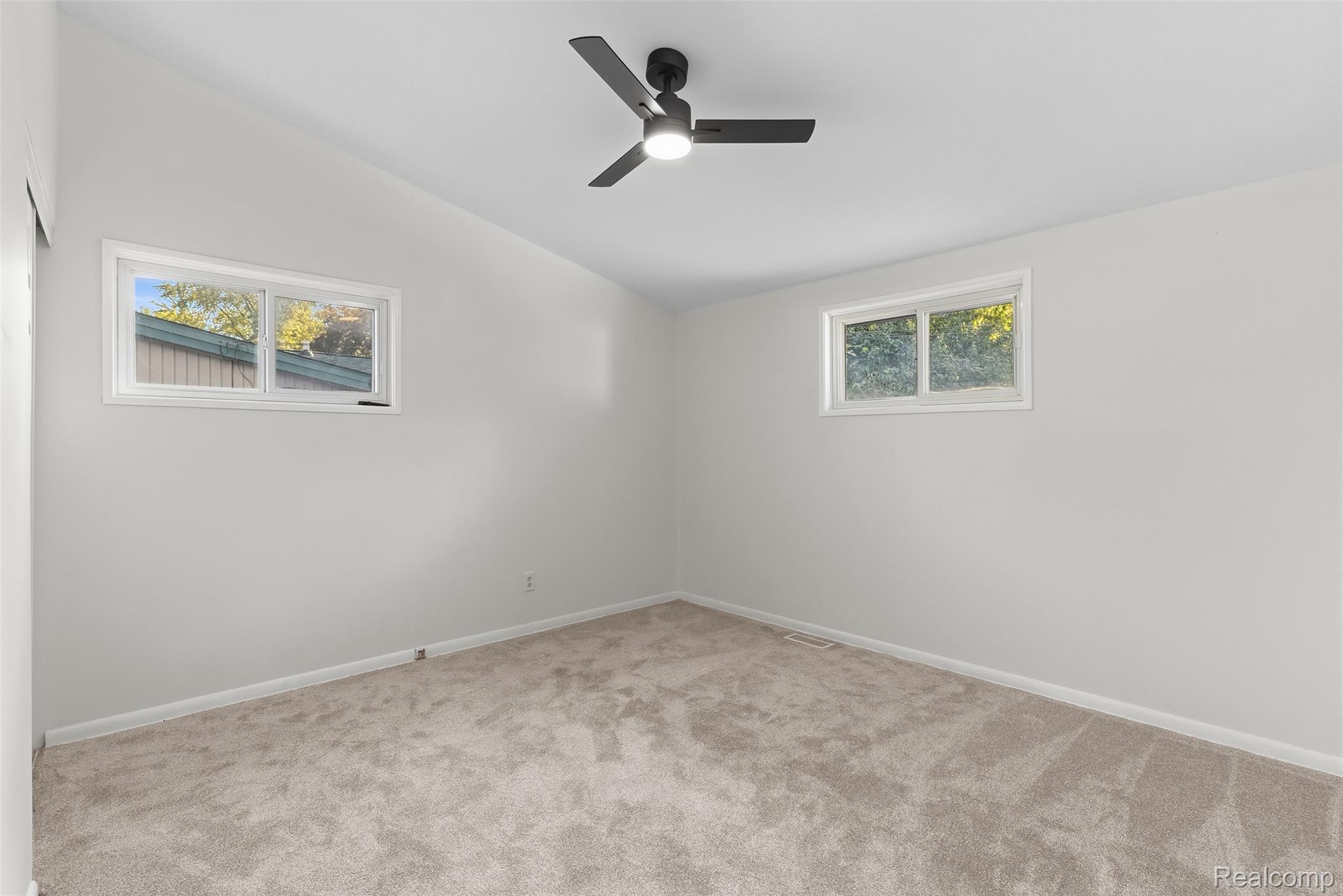 9101 Merriman Road Livonia, MI 48150 - Photo 21 of 41 Vaulted ceiling with a contemporary ceiling fan and two windows, complemented by light-toned carpeting and neutral wall tones