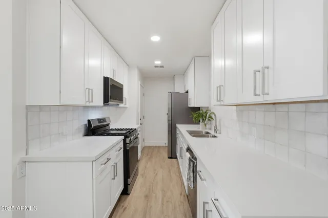 a kitchen with granite countertop white cabinets and stainless steel appliances