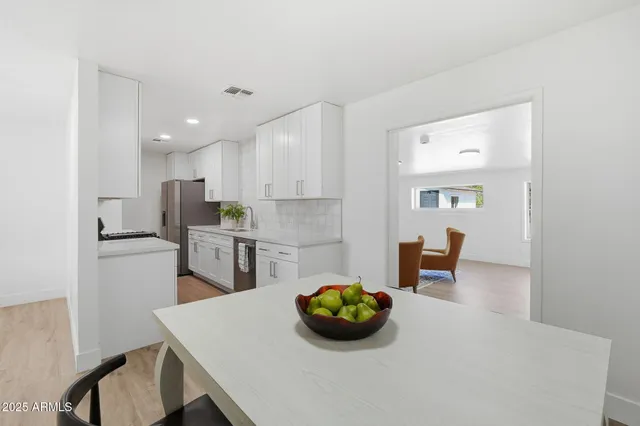 a kitchen with stainless steel appliances a table and chairs in it