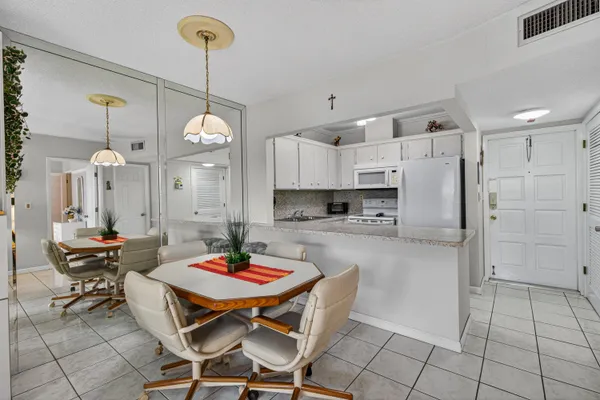 a kitchen with stainless steel appliances kitchen island granite countertop a dining table chairs and a refrigerator