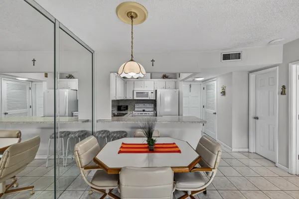 a room with stainless steel appliances a dining table and chairs