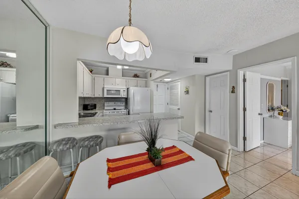a room with stainless steel appliances lots of white furniture a rug and a chandelier