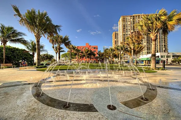 a view of a swimming pool with a lawn chairs and palm trees