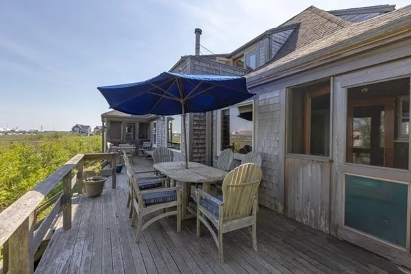 a view of a roof deck with table and chairs under an umbrella with wooden floor