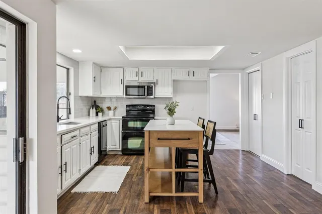 a kitchen with stainless steel appliances granite countertop a white cabinets and wooden floor