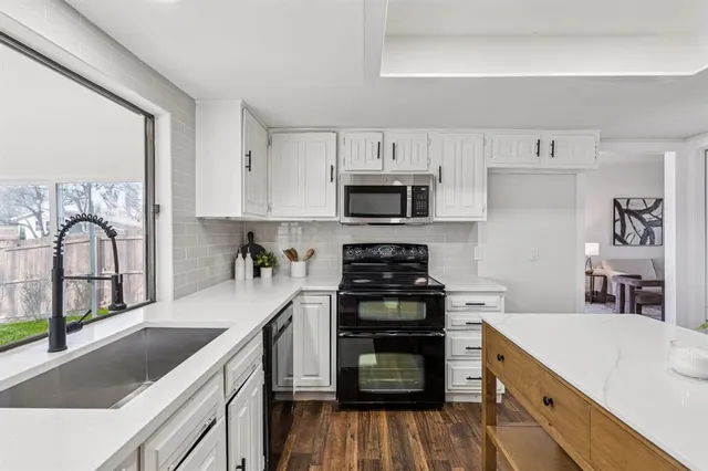 a kitchen with stainless steel appliances granite countertop a stove top oven a sink dishwasher and a refrigerator with wooden floor