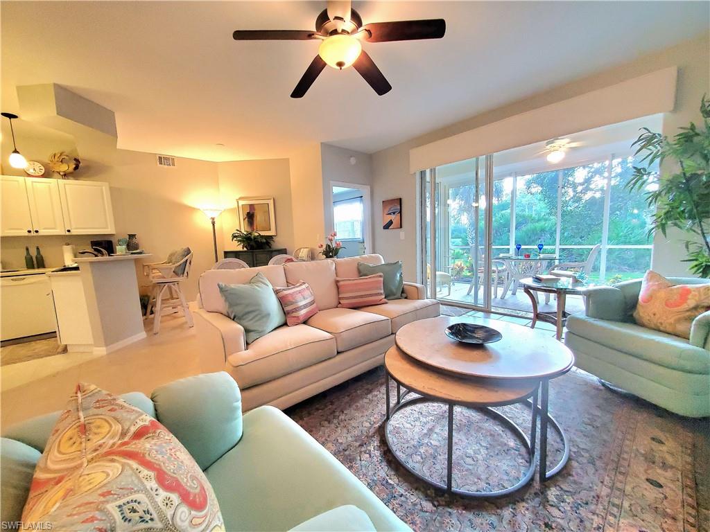 925 Eastham Way, Unit J102 Naples, FL 34104 - Photo 2 of 13 a living room with furniture a lamp and a large window