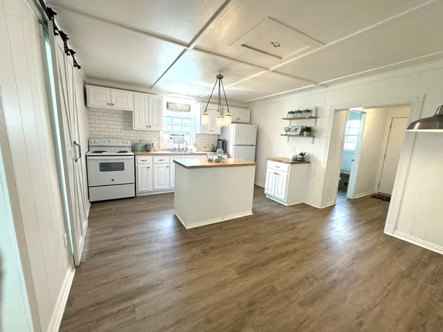 a kitchen with a refrigerator a sink and wooden floor