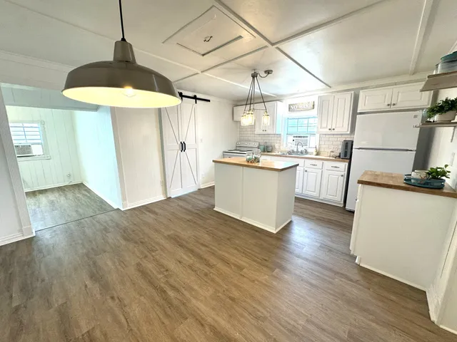 a kitchen with stainless steel appliances wooden floor and a refrigerator