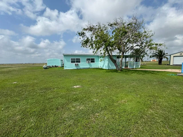 a view of a house with a big yard and large trees