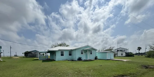 a view of a house with a big yard and large trees
