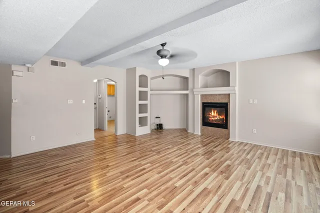 a view of empty room with wooden floor and fireplace