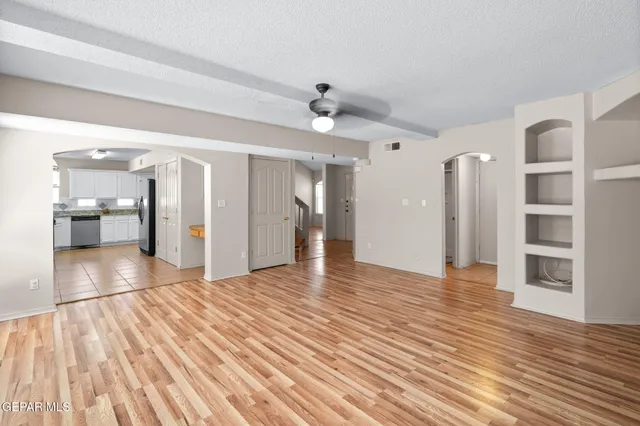 a view of empty room with wooden floor and kitchen view