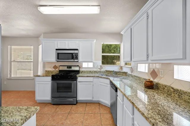 a kitchen with stainless steel appliances granite countertop a stove a sink and a microwave