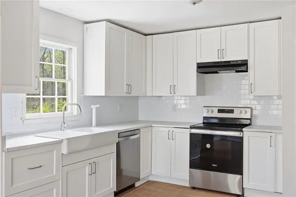 a kitchen with white cabinets and appliances