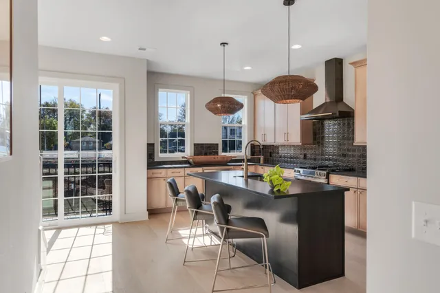 an open kitchen with granite countertop a stove a sink a dining table and chairs with floor to ceiling window