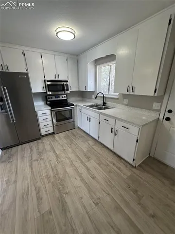 a kitchen with granite countertop a refrigerator a sink dishwasher stove and white cabinets