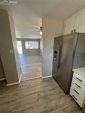 a view of a refrigerator in kitchen and an empty room with wooden floor