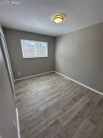 an empty room with wooden floor and window