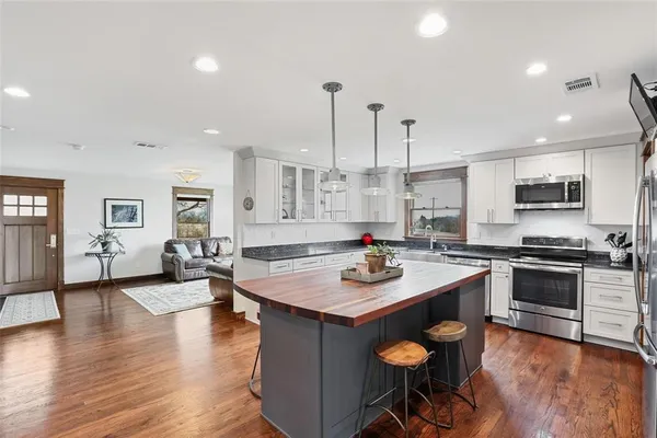 a kitchen with stainless steel appliances granite countertop a stove top oven a sink a counter space and living room view