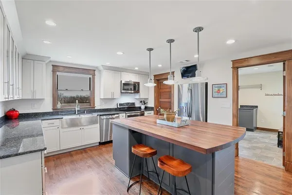 a kitchen with stainless steel appliances granite countertop a sink dishwasher and a refrigerator with wooden floor