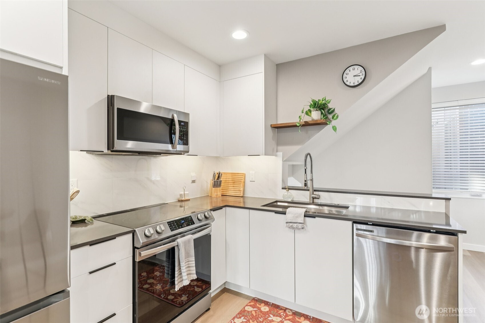7514 43rd Avenue South, Unit B Seattle, WA 98118 - Photo 8 of 40 a kitchen with stainless steel appliances a stove a microwave and white cabinets