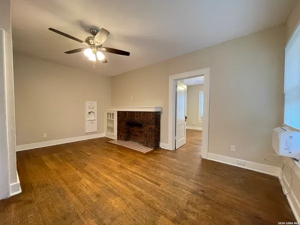 a view of empty room with wooden floor and fireplace