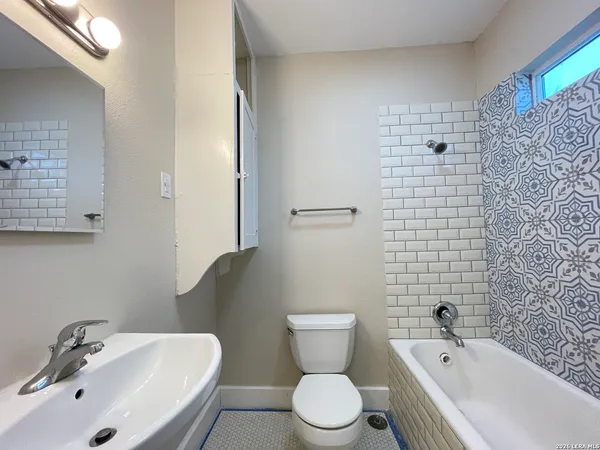 a bathroom with a toilet a sink a mirror and bathtub