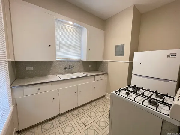 a kitchen with sink a stove and white cabinets