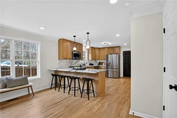 a large kitchen with stainless steel appliances granite countertop a sink dishwasher a stove top oven a dining table and chairs with wooden floor