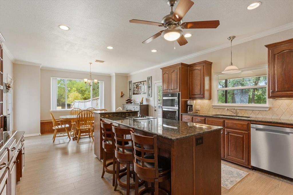 111 Spring Creek Street Waco, TX 76705 - Photo 14 of 40 Spacious kitchen featuring an expansive center island with seating, dark wood cabinetry, stainless steel appliances, and wood-finish flooring