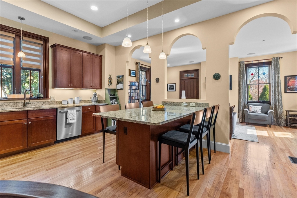a kitchen with stainless steel appliances kitchen island granite countertop wooden floors and wooden cabinets