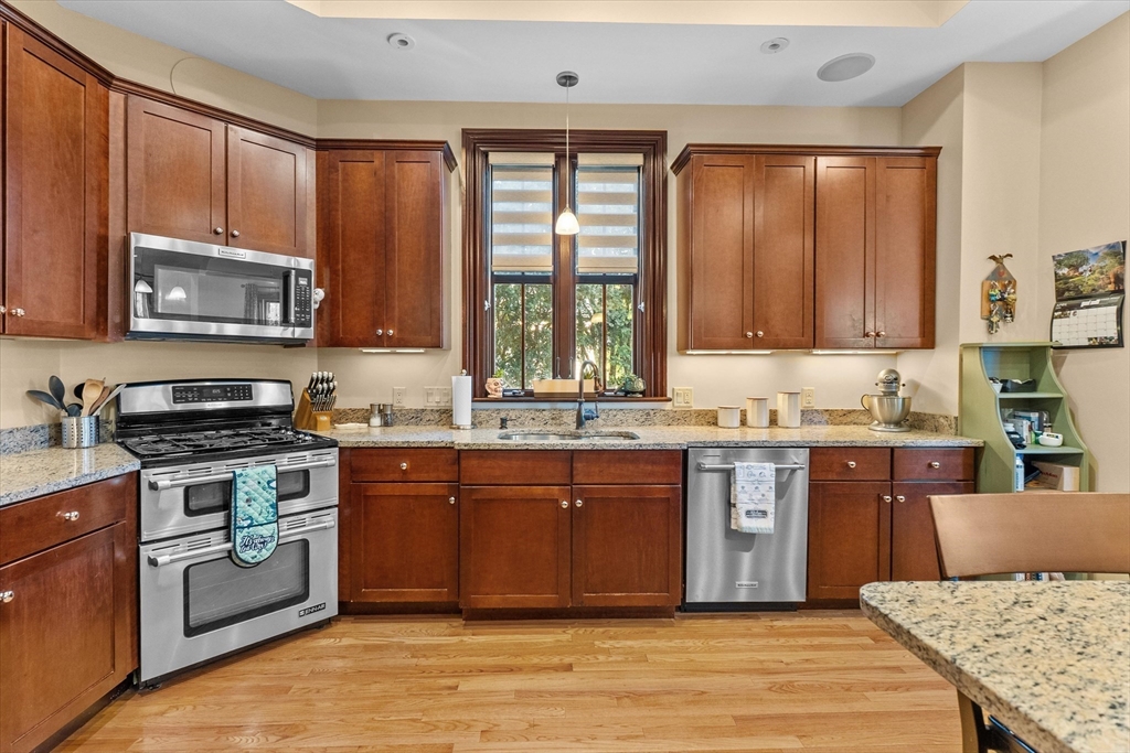 7 Winter Street, Unit 2 Salem, MA 01970 - Photo 7 of 42 a kitchen with stainless steel appliances granite countertop a stove a sink dishwasher a microwave oven and a refrigerator with wooden cabinets