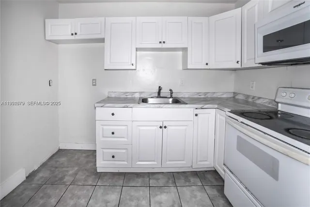 a white kitchen with granite countertop white cabinets