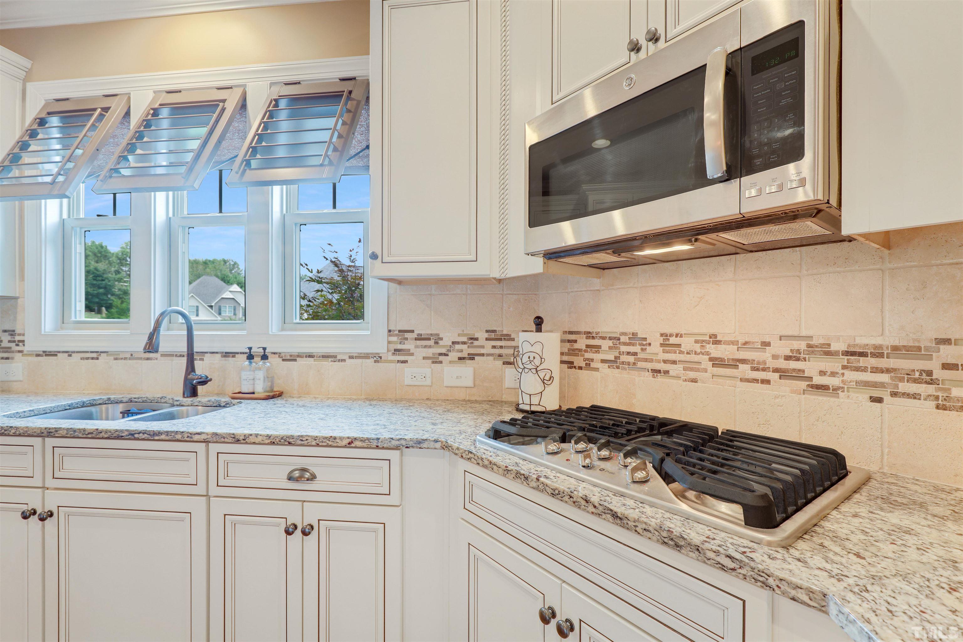 4312 Glengrove Road Raleigh, NC 27616 - Photo 15 of 50 a kitchen with granite countertop stainless steel appliances a stove a microwave and cabinets