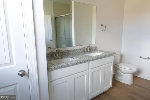 a bathroom with a granite countertop sink and a toilet