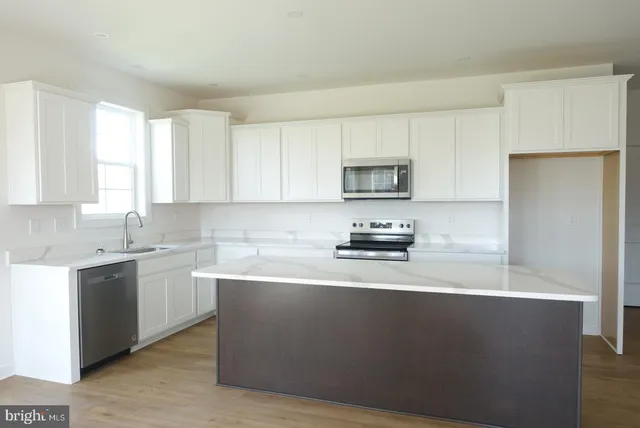 a kitchen with stainless steel appliances a sink a stove a microwave a sink a refrigerator and cabinets