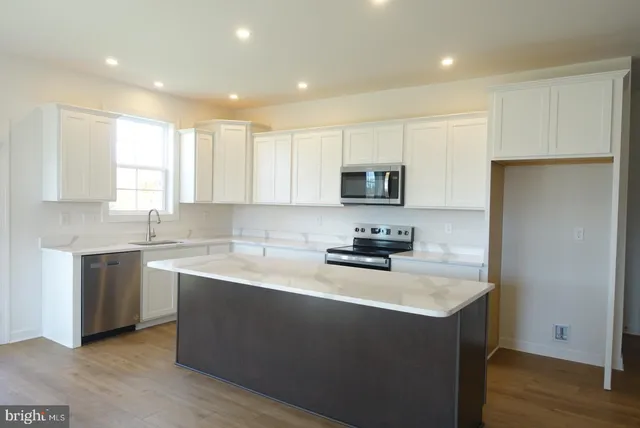 a kitchen with a sink a stove a refrigerator a center island and a window