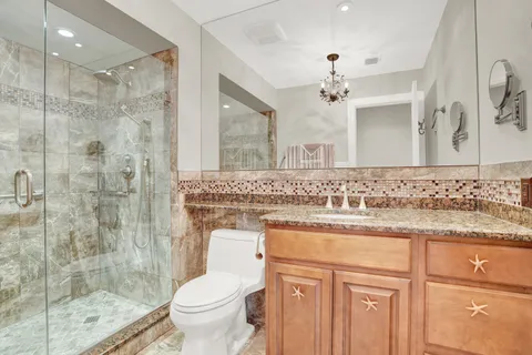 a bathroom with a granite countertop sink a toilet a mirror and shower
