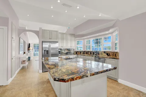 a large kitchen with kitchen island a large counter top stainless steel appliances and cabinets