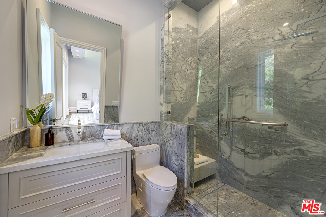 930 Roscomare Road Los Angeles, CA 90077 - Photo 45 of 54 a bathroom with a granite countertop toilet a sink and a mirror