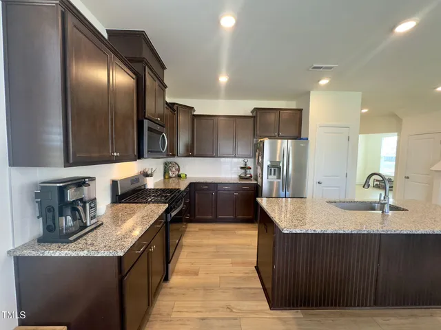 a large kitchen with stainless steel appliances granite countertop a counter top a sink and a refrigerator