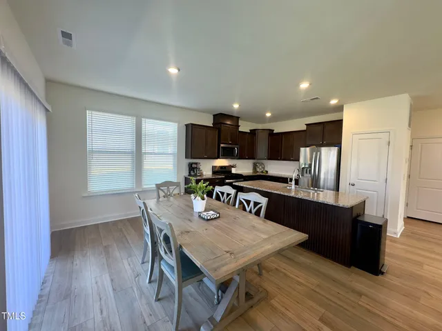 a kitchen with stainless steel appliances granite countertop a kitchen island hardwood floor sink stove dining table and chairs