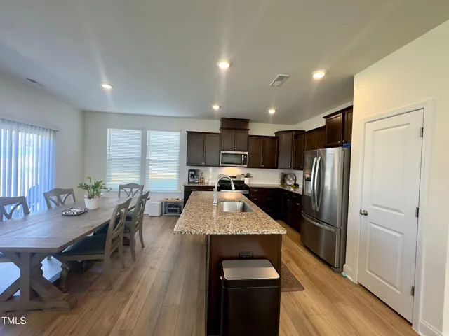 a large kitchen with a table chairs refrigerator and wooden floor