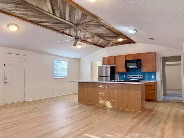 a kitchen with kitchen island granite countertop wooden cabinets and a stainless steel appliances