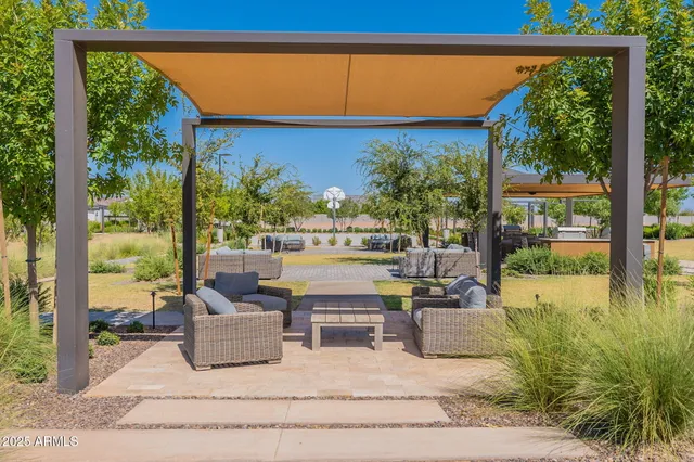 a view of a patio with couches table and chairs under an umbrella with palm trees