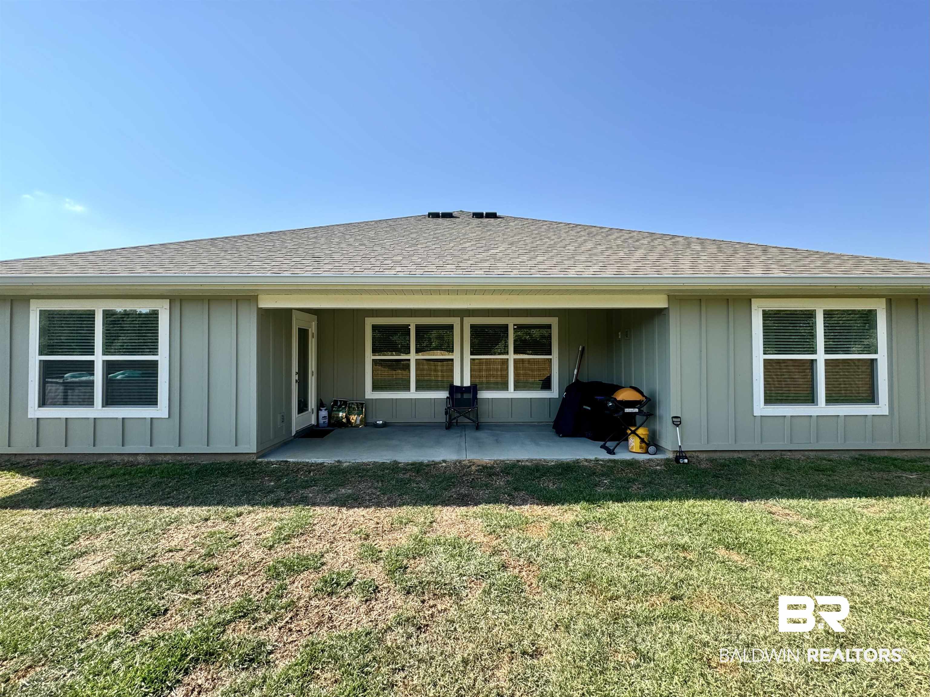 24216 Ringneck Loop Elberta, AL 36530 - Photo 12 of 23 Rear view of house featuring board and batten siding, roof with shingles, a patio, and a yard