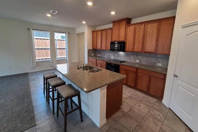 a kitchen with kitchen island granite countertop wooden cabinets and a sink