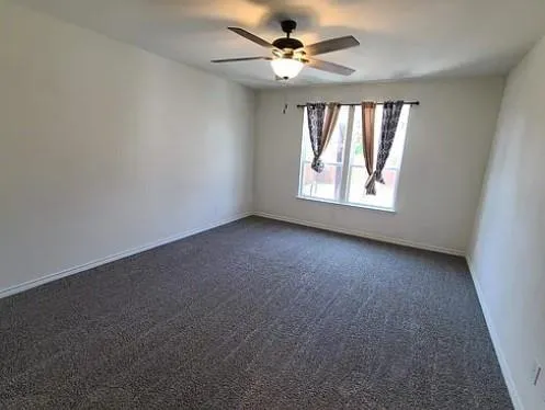 an empty room with a window and a fan